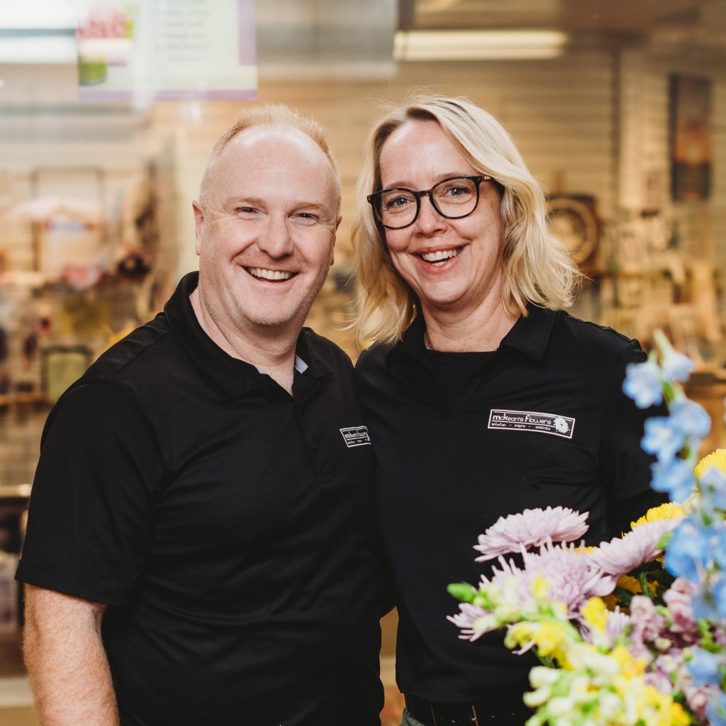 Two workers standing together in their flower shop.