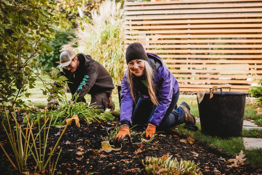 Two workers cleaning up a flower bed.